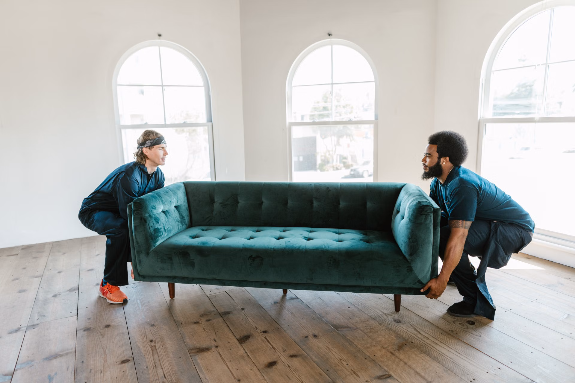 Two crew members lifting a sofa together